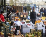 کارگر در حال گذر از کنار بساط میوه‌فروشی با نگاه حسرت‌آمیز