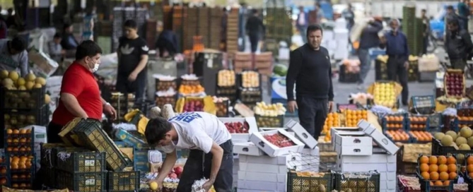 کارگر در حال گذر از کنار بساط میوه‌فروشی با نگاه حسرت‌آمیز