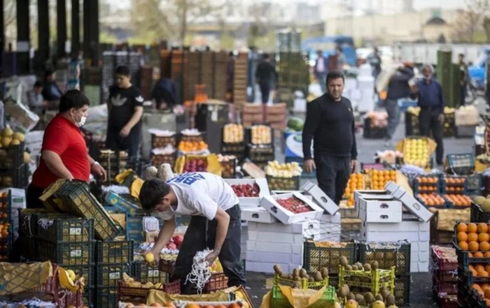 کارگر در حال گذر از کنار بساط میوه‌فروشی با نگاه حسرت‌آمیز