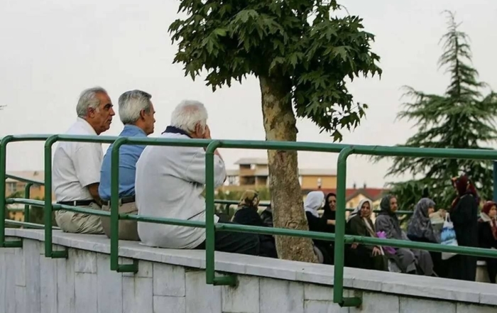 تصویر نمادین یک بازنشسته و اسکناس‌های ناچیز در کنار سبد کالای گران قیمت نوروزی